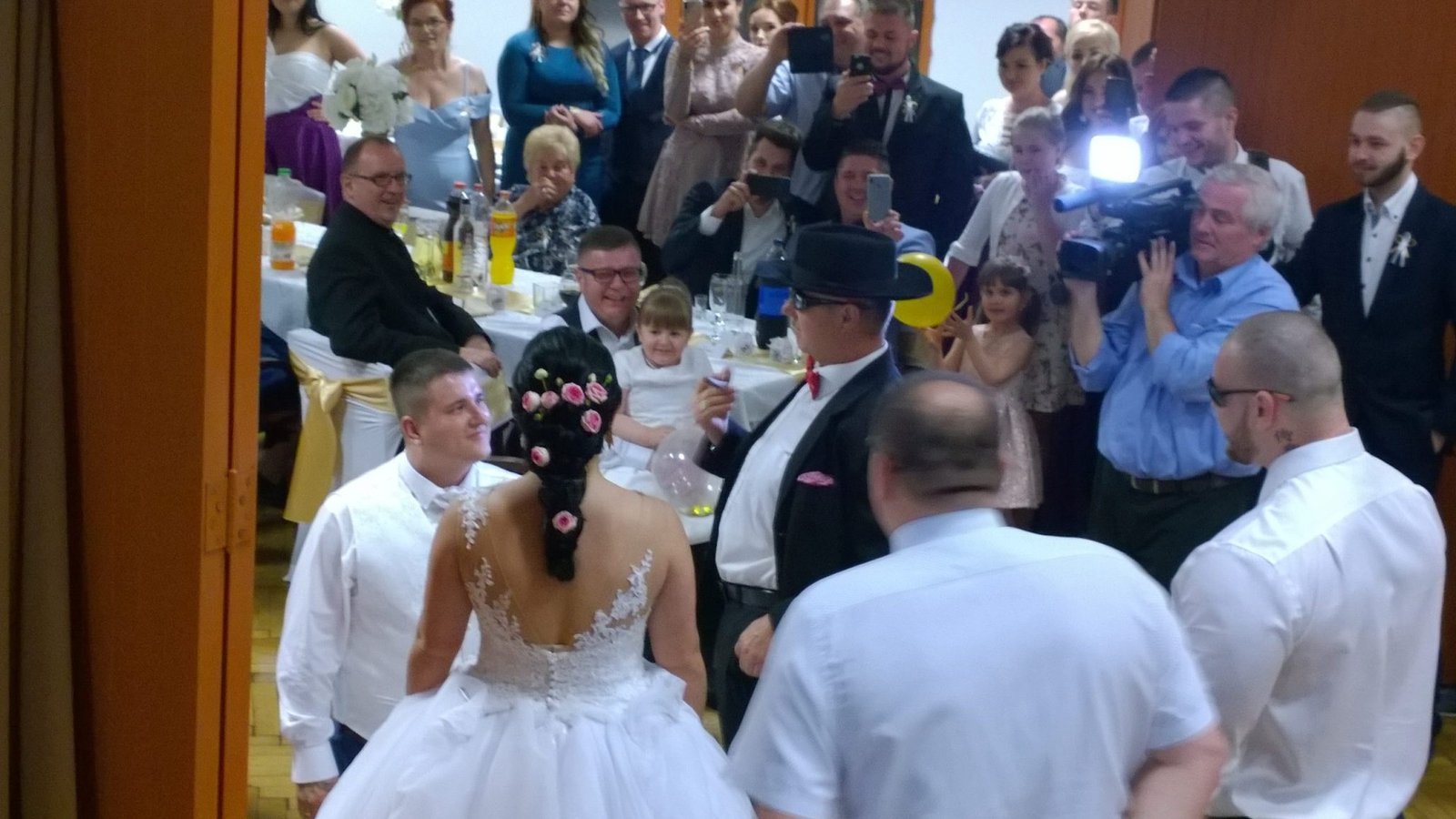 Esküvői vendégek gyűlnek össze, telefonnal fényképezve a pillanatot