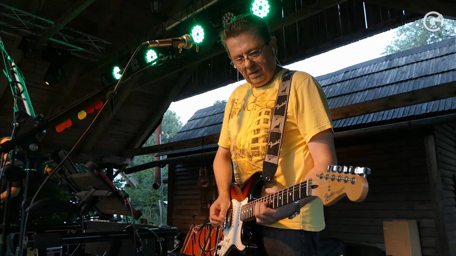 A RITMO zenekar gitárosa szabadtéri, fedett színpadon lép fel napfényes környezetben